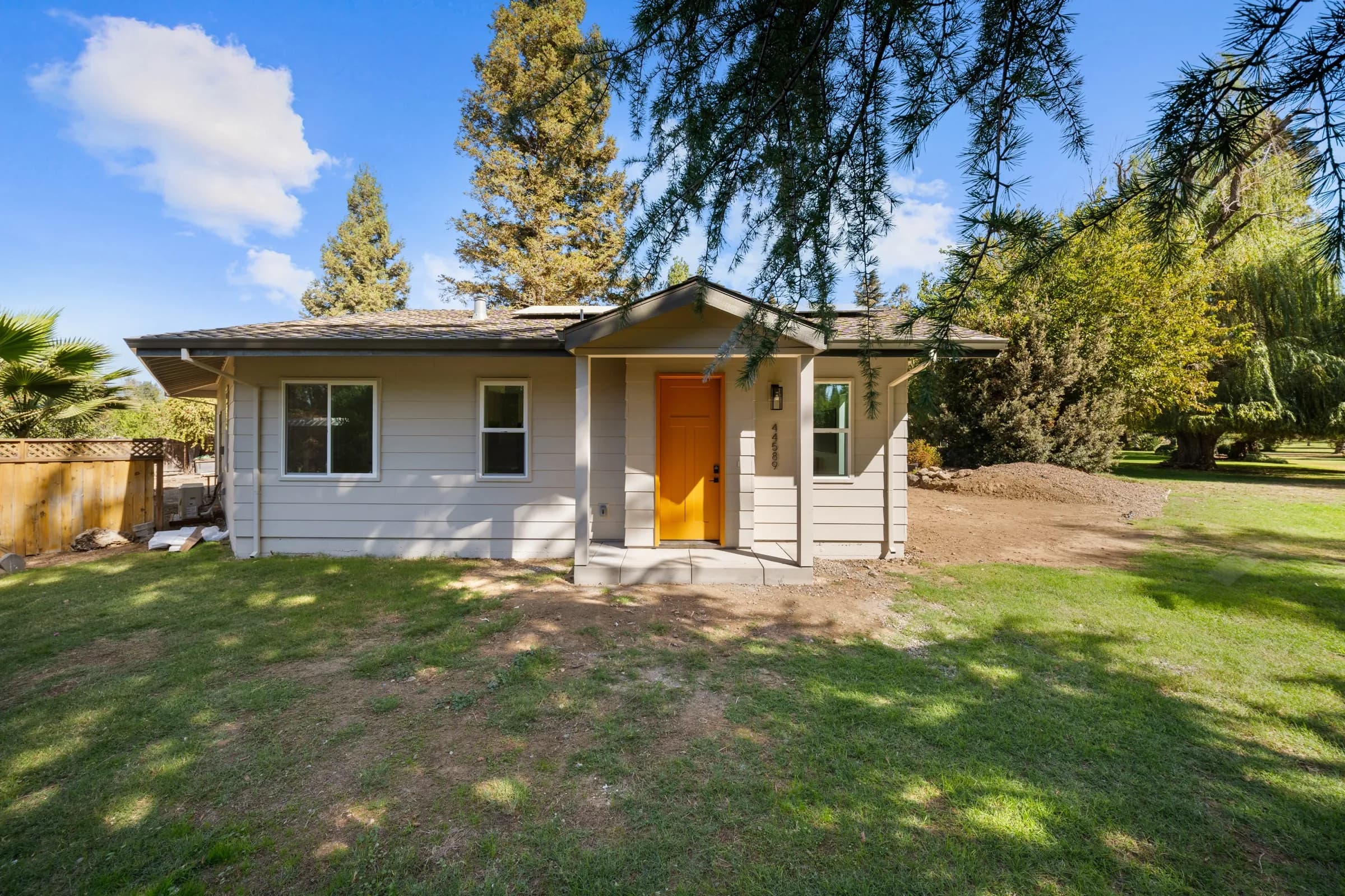A finished single-story ADU with an orange front door and a lawn