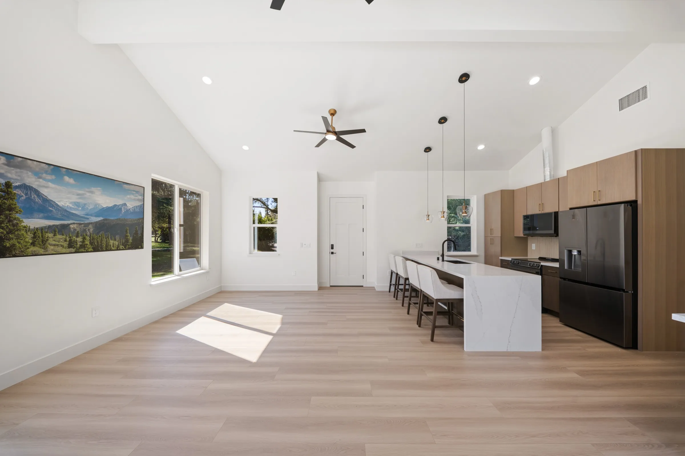 An ADU kitchen with a long white island and pendant lights